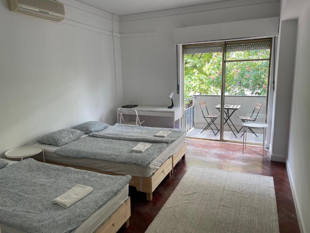 a bedroom with two beds and a balcony with a table at L83 - rooms and apartments in Lisbon