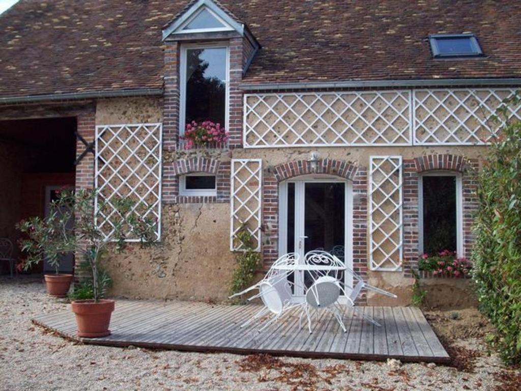 uma casa com uma mesa e cadeiras num alpendre em Gîte Douchy-Montcorbon-Douchy, 3 pièces, 5 personnes - FR-1-590-105 