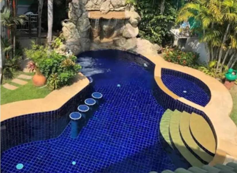 a swimming pool with blue tiles in a backyard at Private Pattaya Resort in Nong Prue
