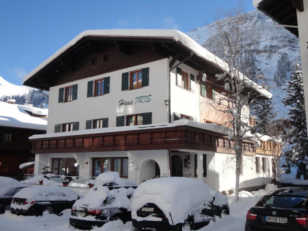 ein schneebedecktes Gebäude mit davor geparkt in der Unterkunft Pension Iris in Lech am Arlberg