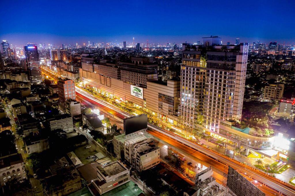 a city lit up at night with traffic at The Bazaar Hotel Bangkok in Bangkok