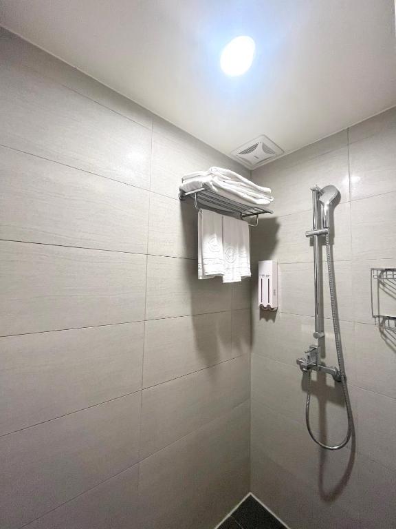 a shower in a bathroom with white tiles at Hotel Puri in Taipei
