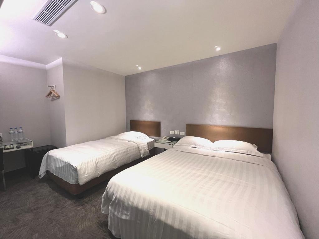 a hotel room with two beds with white sheets at Hotel Puri in Taipei