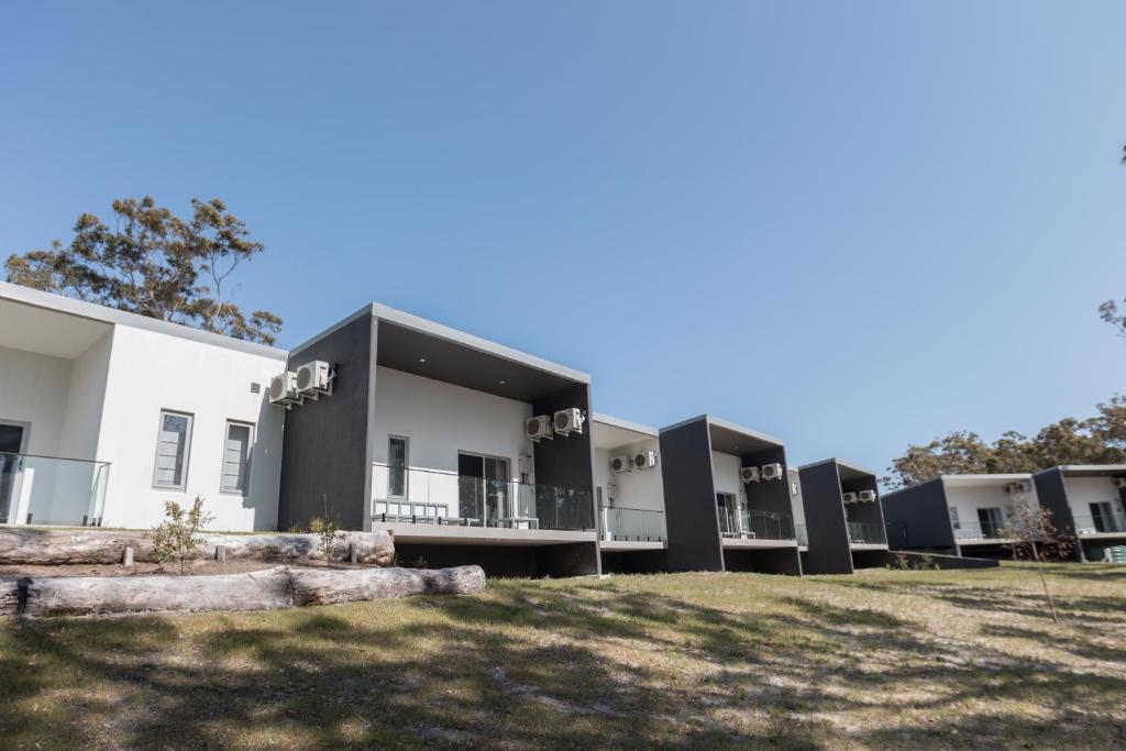 a row of modular buildings with a grass field at Beach & Bay Stay Motel in Callala Beach