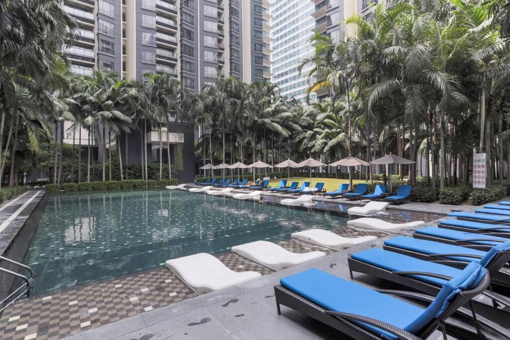uma piscina com espreguiçadeiras e palmeiras em Large 3-Bedroom Modern Resort Style KLCC Apartment em Kuala Lumpur