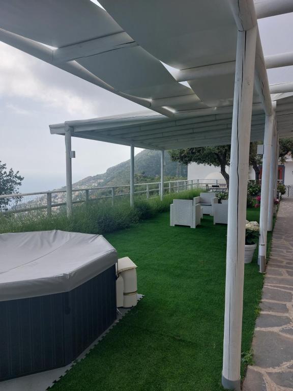 a white pergola on a lawn with a view at Villa Cimea in Furore