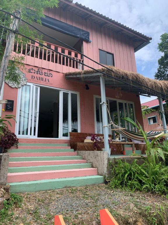 una casa rosa con escaleras delante en DAHLIA Guesthouse en Koh Rong Sanloem