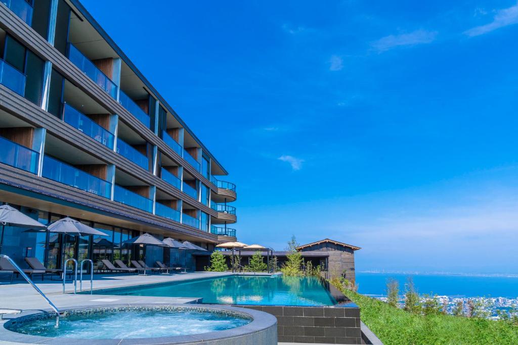 别府ANA InterContinental Beppu Resort & Spa by IHG的一座酒店,在后面设有一个游泳池和大海