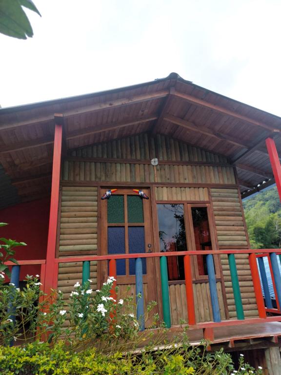 a log cabin with a porch and a door at Las cabañas del escobo - CABAÑA TUCÁN in Nimaima
