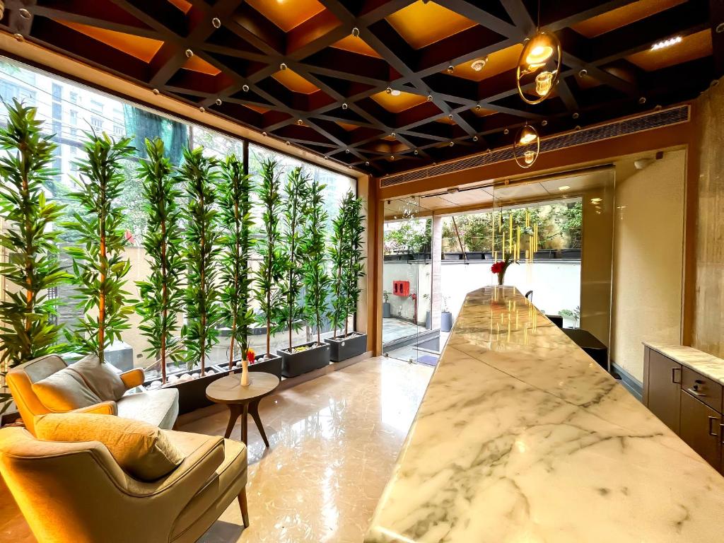 Großes Zimmer mit einem großen Fenster mit Pflanzen in der Unterkunft Morvee Hotels Alipore Kolkata in Kalkutta