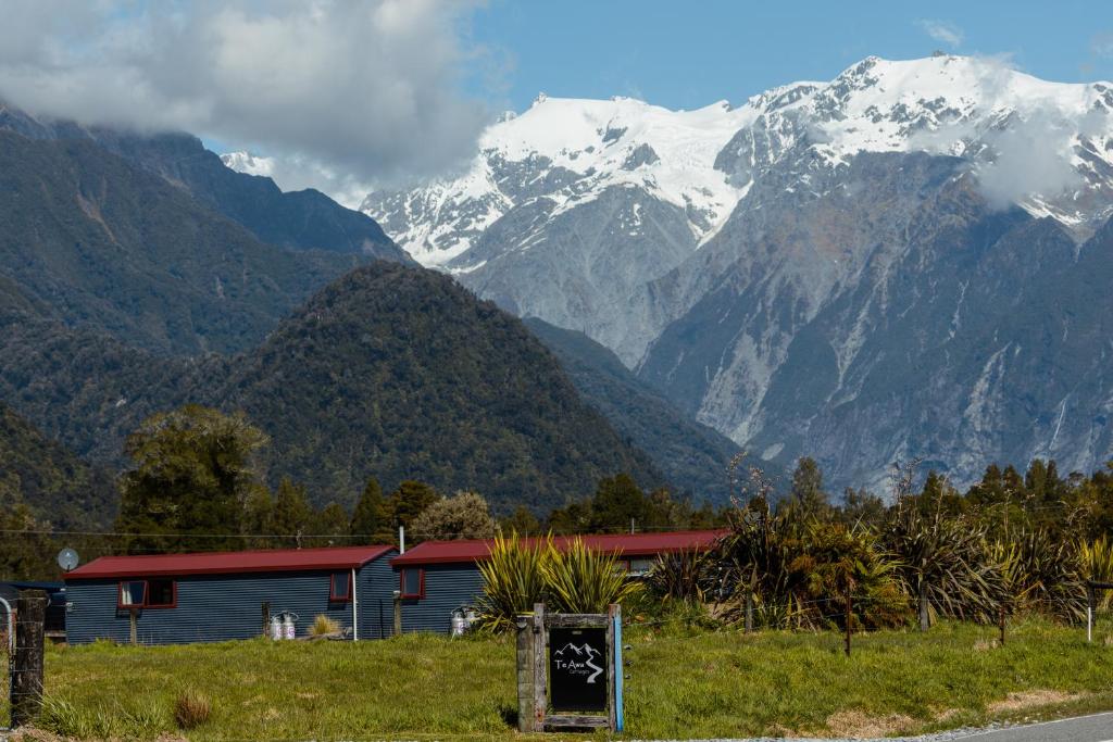 a building with snow capped mountains in the background at Te Awa Cottages in Franz Josef