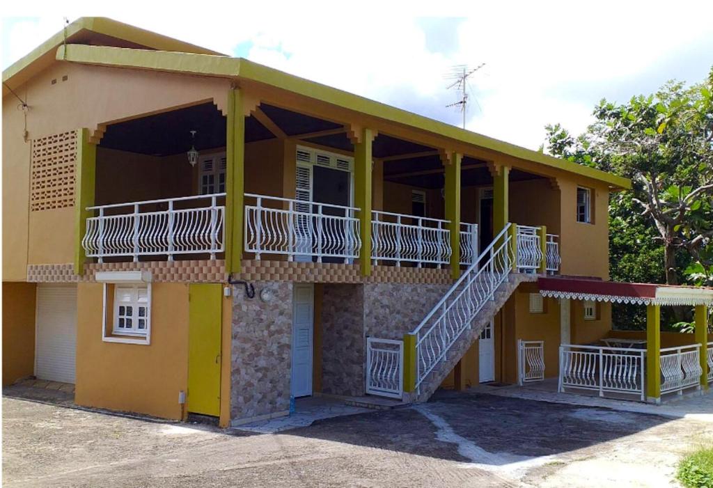 Cette maison jaune dispose d'un balcon et d'un escalier. dans l'établissement Appartement de 2 chambres avec terrasse amenagee et wifi a Le Robert, à Le Robert