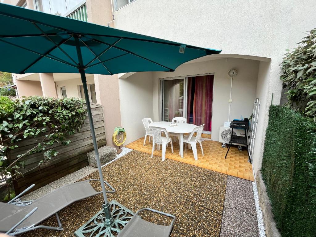 a patio with a table and chairs and an umbrella at Studio climatisé avec jardin et plage à 250m in Saint-Mandrier-sur-Mer