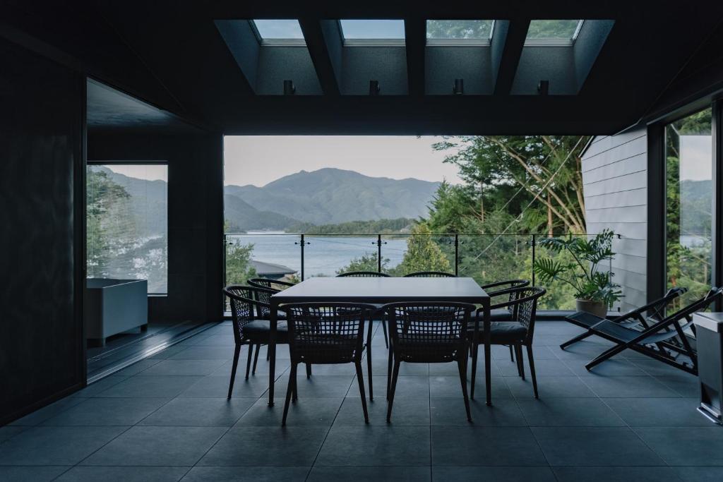 una sala da pranzo con tavolo, sedie e una grande finestra di hotel norm air a Fujikawaguchiko