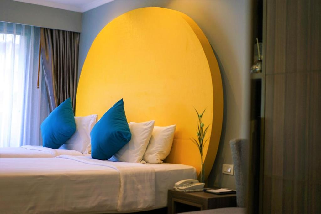 a hotel room with a bed with blue pillows at FuramaXclusive Sukhumvit in Bangkok