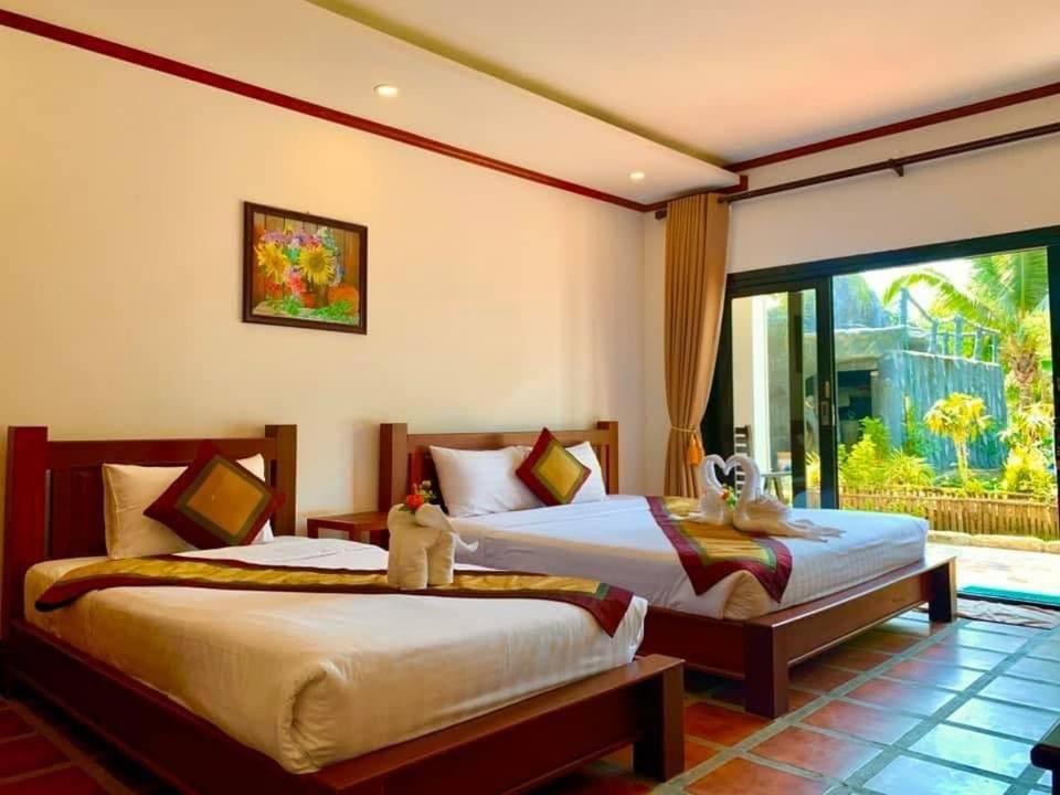 a bedroom with two beds and a large window at Vang Vieng Savanh Sunset View Resort in Vang Vieng