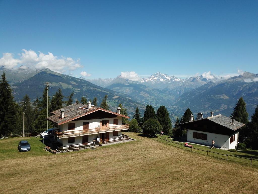 a house on a hill with mountains in the background at Maison Dahu - Sci, passeggiate e sport a Pila - Alloggio ad uso turistico - VDA - Gressan - n 0012 in Pila