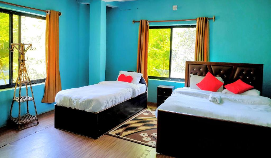 two beds in a room with blue walls and windows at Jungle Heaven Hotel and Cottage in Bhurkīā