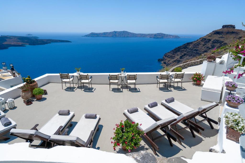 a patio with chairs and tables and a view of the ocean at Lithies Traditional Homes in Firostefani