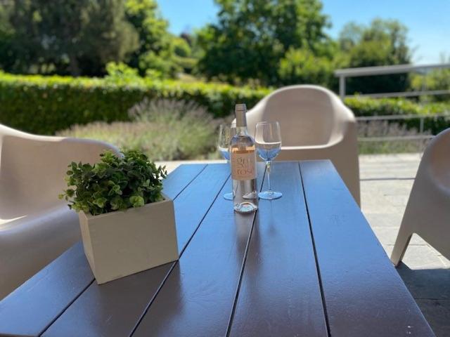 una mesa de madera con una botella de vino y dos copas en "Chez Mima" - à deux pas de Durbuy!, en Durbuy