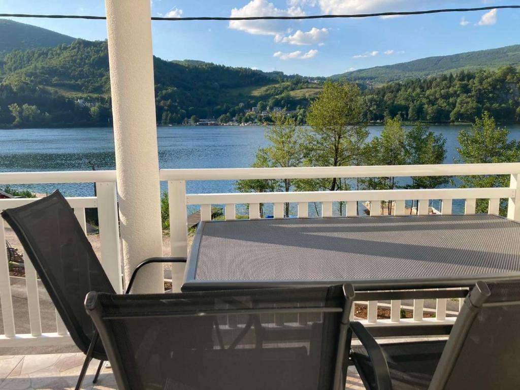 a table and chairs on a porch with a view of a lake at Villa Pliva Lake Jajce in Jajce