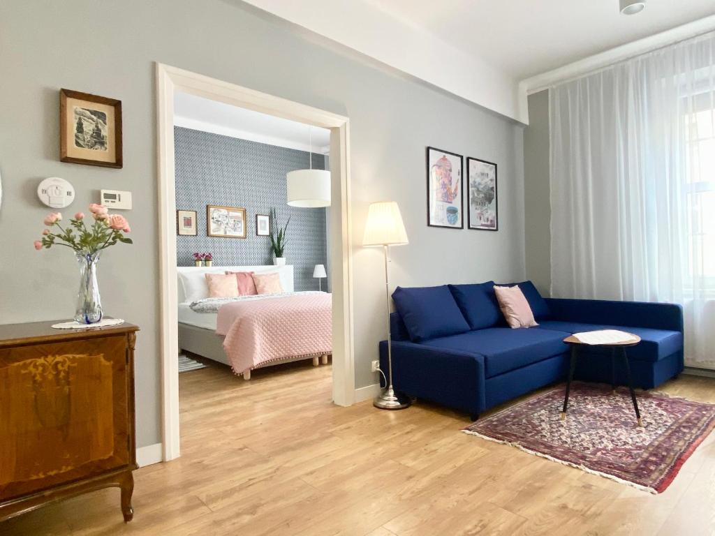 a living room with a blue couch and a bedroom at Smile Apartments Center Kraków Old Town in Kraków