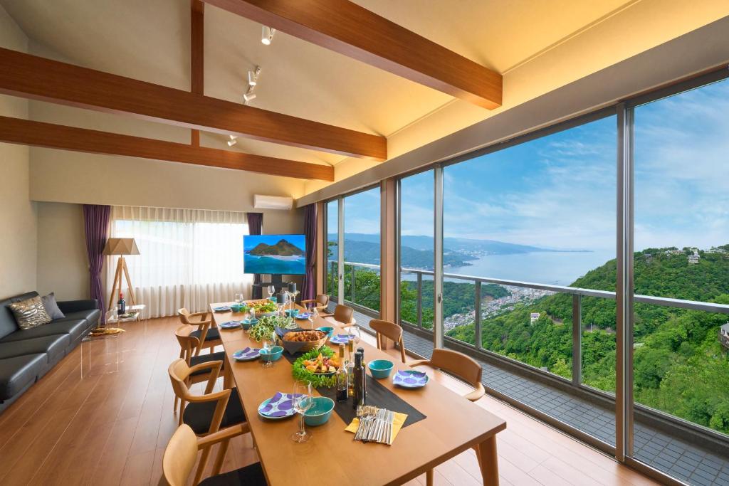 a dining room with a table and chairs and large windows at Suite Villa Ocean View Minami-Atami in Atami