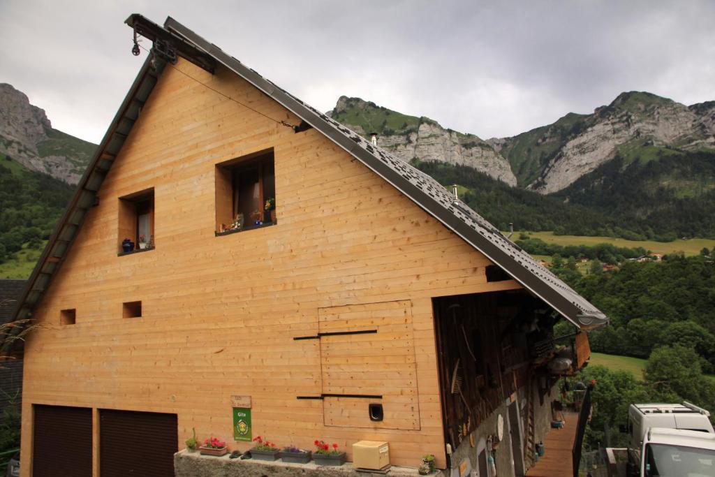 Une grande grange en bois avec des montagnes en arrière-plan dans l'établissement chalet la tournette, à Montmin