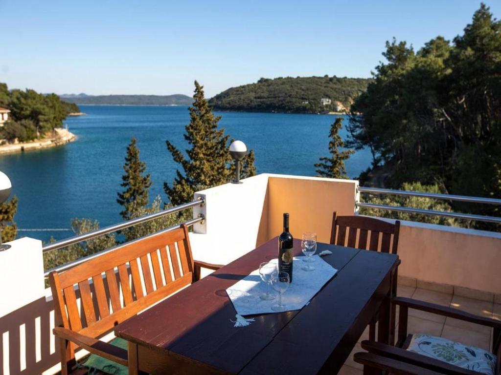 a wooden table with a bottle of wine on a balcony at Apartment Brunac in Brbinj