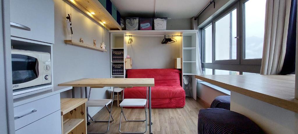 una piccola cucina con divano rosso in una casetta di Studio fonctionnel 16m2 avec vue panoramique a Puy-Saint-Vincent