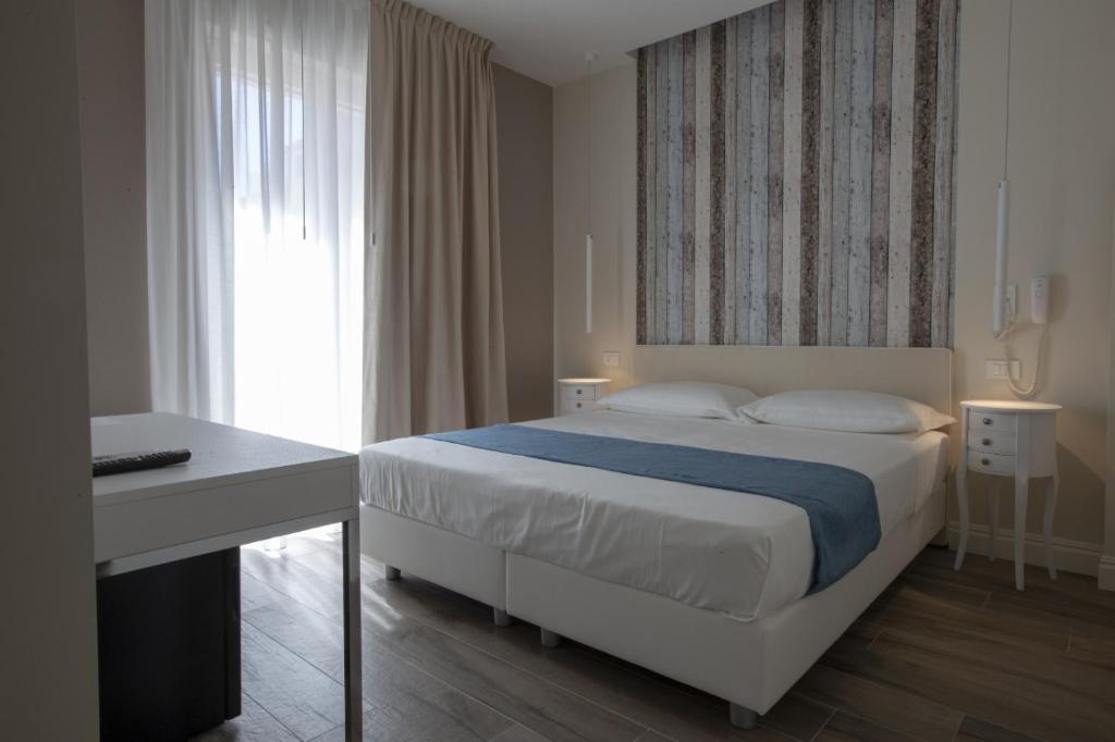 a bedroom with a bed and a desk and a window at Luxmarì Hotel & Spa in Castellammare del Golfo