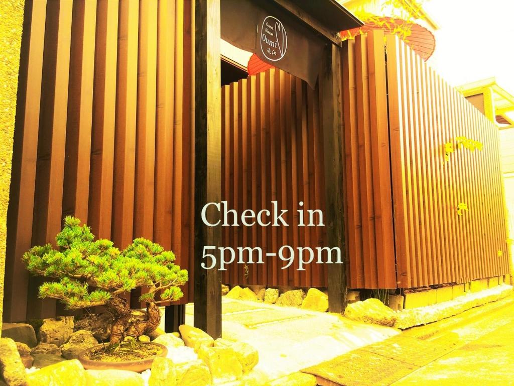 a building with a tree in front of a fence at Guest House Oumi in Kyoto