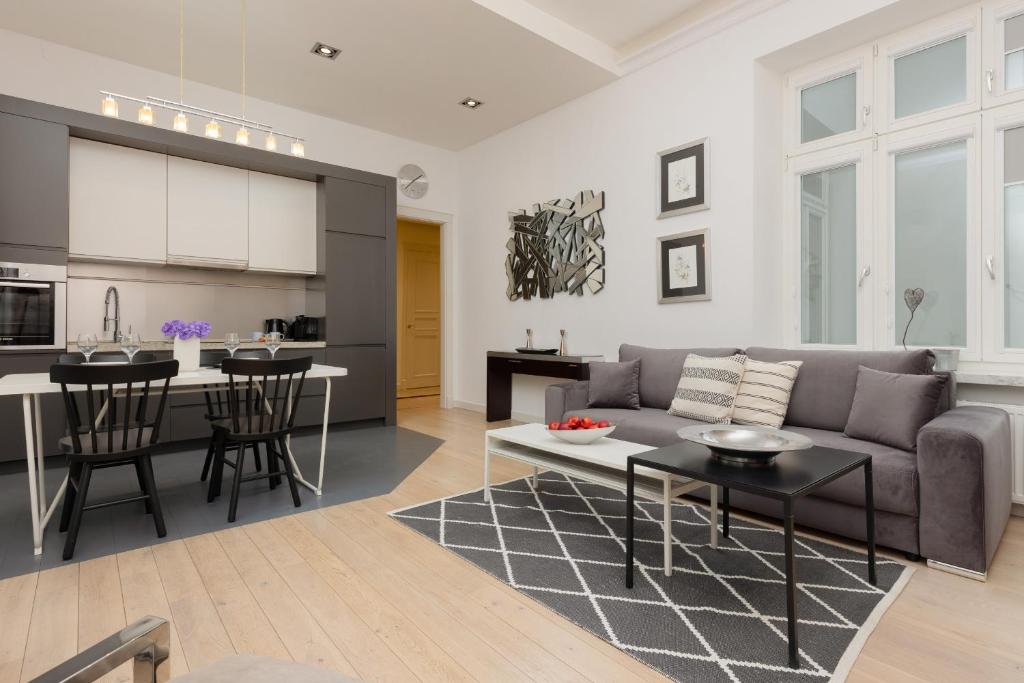 uma sala de estar e cozinha com um sofá e uma mesa em Western Side of Vistula River Apartment Radna by Renters em Varósvia