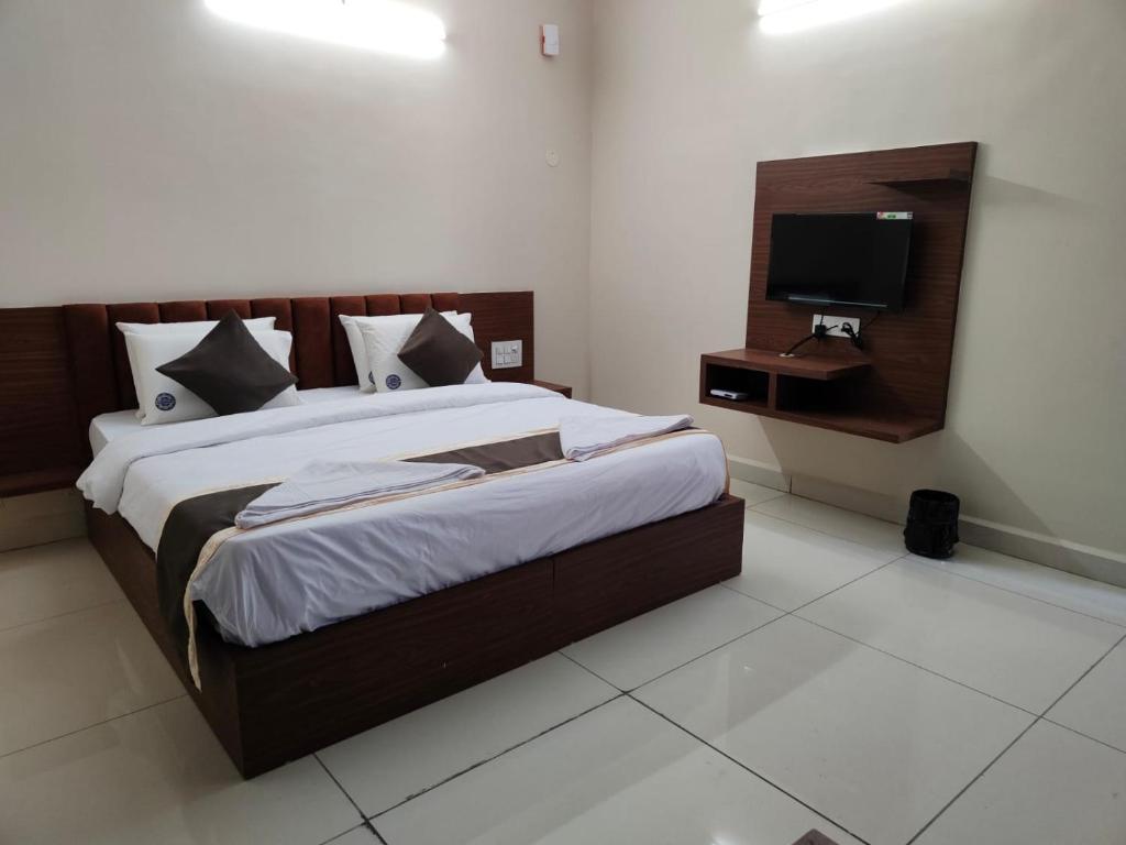 Hotel Crown Inn في دهرواد: غرفة نوم بسرير كبير وتلفزيون