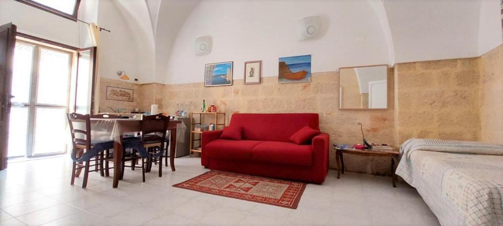 een woonkamer met een rode stoel en een tafel bij Bed & Breakfast Porta d'Oriente in Brindisi