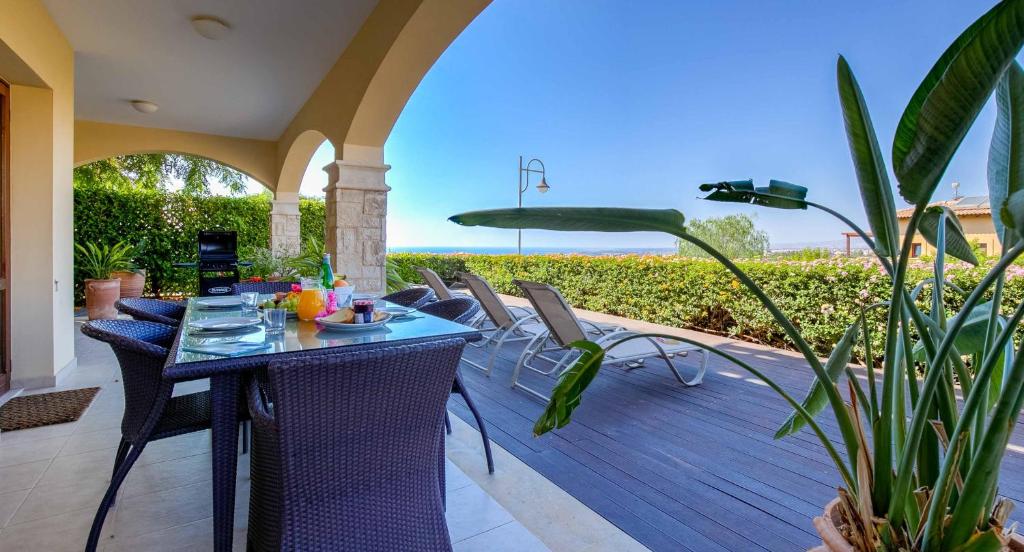 a patio with a table and chairs on a deck at Ground floor Apartment Anthos with Beautiful Sea Views on Aphrodite Hills Resort in Kouklia