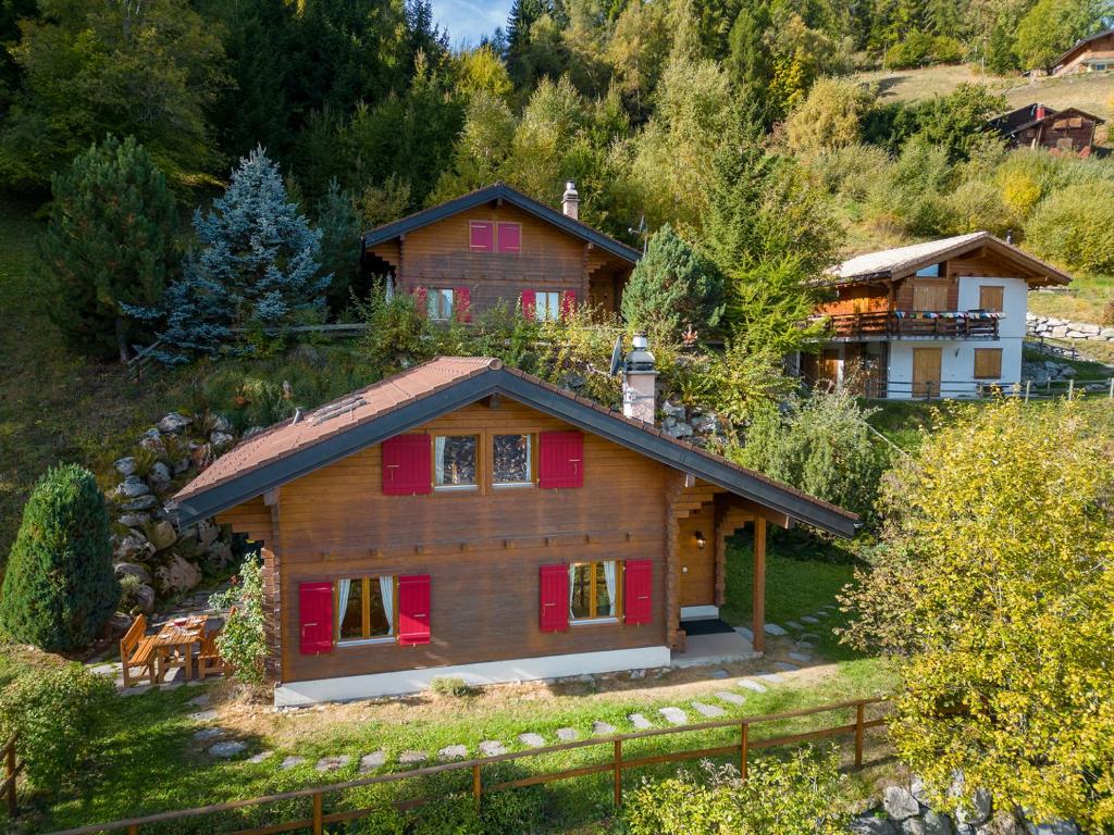 une maison en bois avec volets rouges sur une montagne dans l'établissement Chalet Mar'Mot, à La Tzoumaz