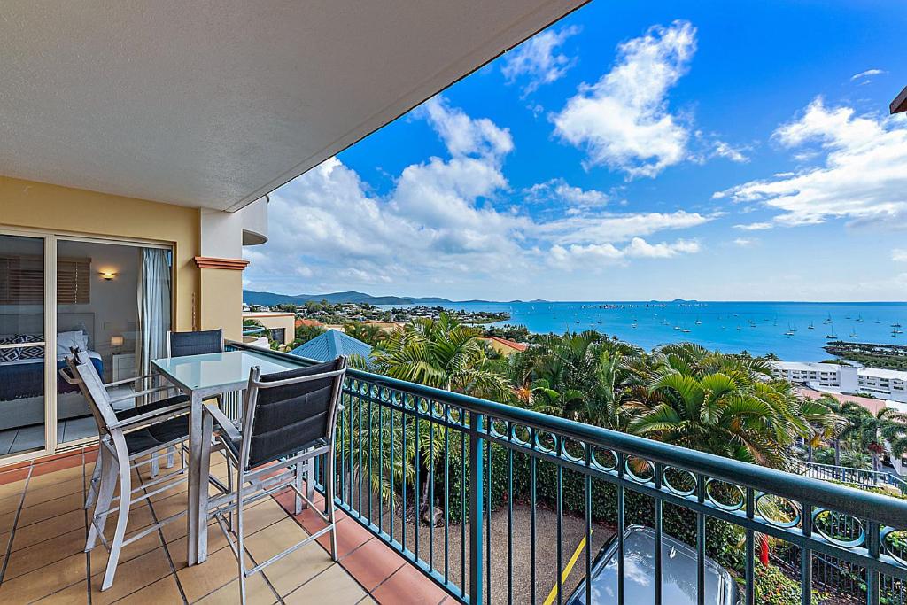 a balcony with a table and chairs and the ocean at Point Break On Airlie in Airlie Beach