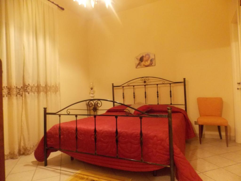 um quarto com uma cama vermelha e uma cadeira em Modica Sikula Relax em Modica