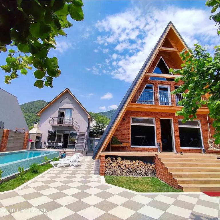 a house with a gambrel roof and a swimming pool at Trigon Villa Family , HOT POOL ,SAUNA,JACUZZI in Gabala