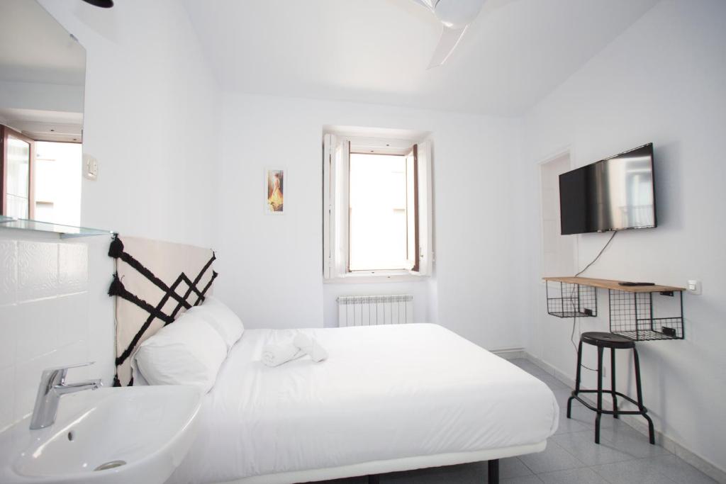 Habitación blanca con cama y lavabo en Gran Via Experience, en Madrid