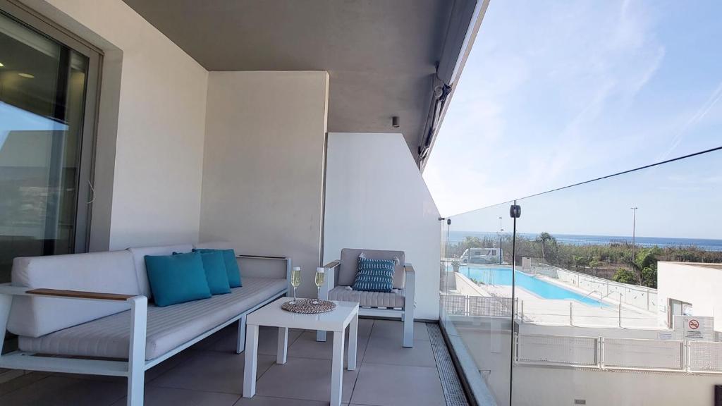 a balcony with a couch and a table and a pool at Panorama Beach - Blue Horizon in Torrox Costa