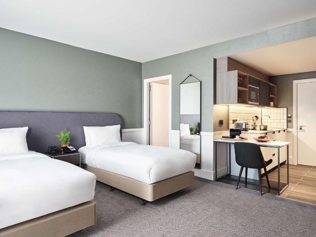 a hotel room with two beds and a kitchen at Hyatt House Manchester in Manchester