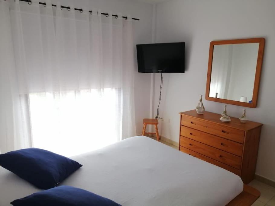 een slaapkamer met een bed, een spiegel en een dressoir bij Idílico adosado en El Mocanal in Mocanal