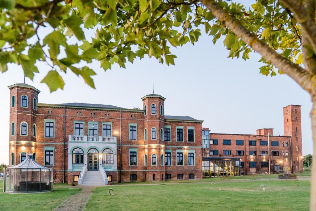 a large brick building with a fountain in front of it at Elbe Resort Alte Ölmühle in Wittenberge