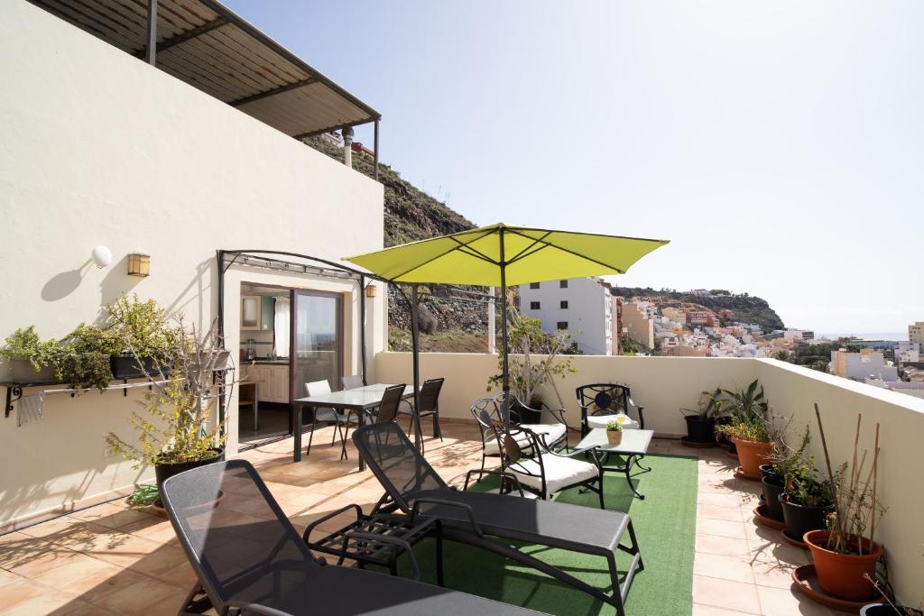 un patio con mesas, sillas y una sombrilla en Holiday House Penthouse in La Gomera, en San Sebastián de la Gomera