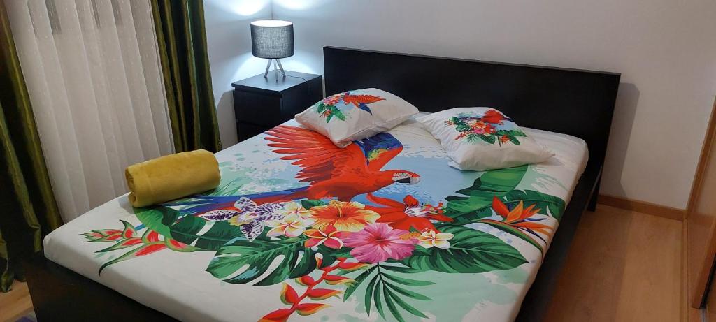 a bed with a colorful bedspread with birds and flowers at Ocean View Flat in Ponta Delgada