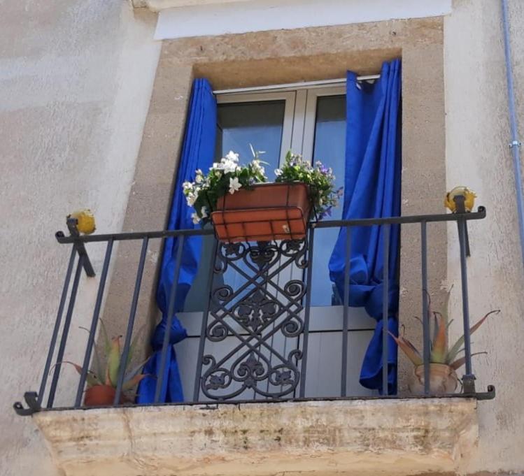 a balcony with blue curtains and flowers and a window at Bed & Breakfast Porta d'Oriente in Brindisi