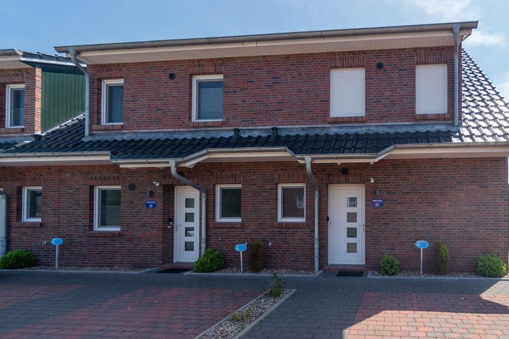 een bakstenen gebouw met witte deuren en een stenen oprit bij Ferienhaus Empora in Bensersiel