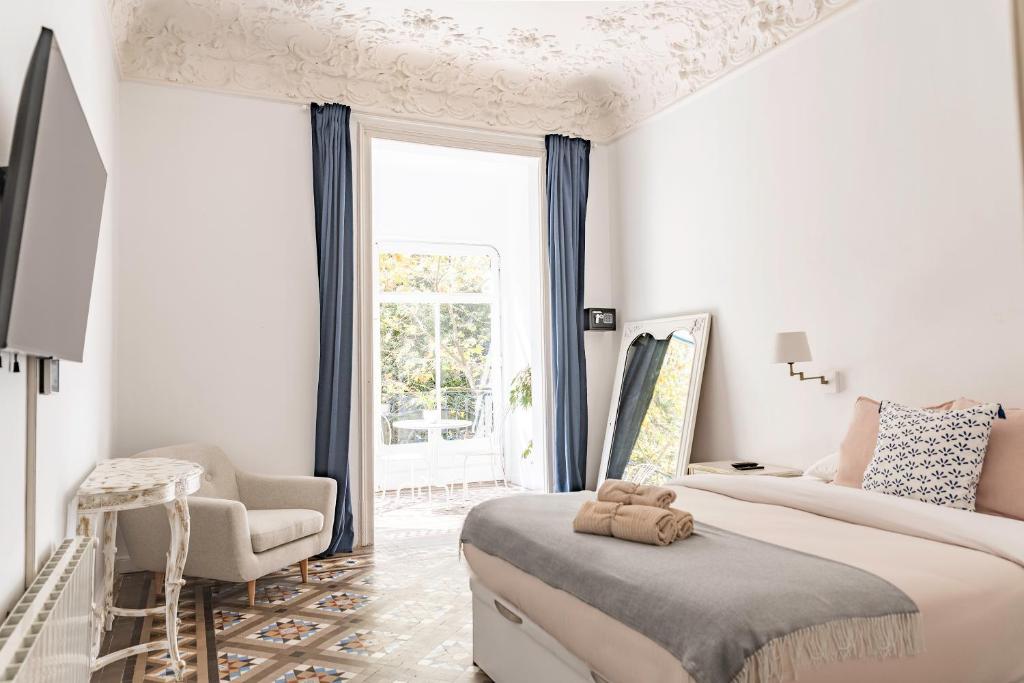 een witte slaapkamer met een groot bed en een stoel bij B-Garden BCN in Barcelona